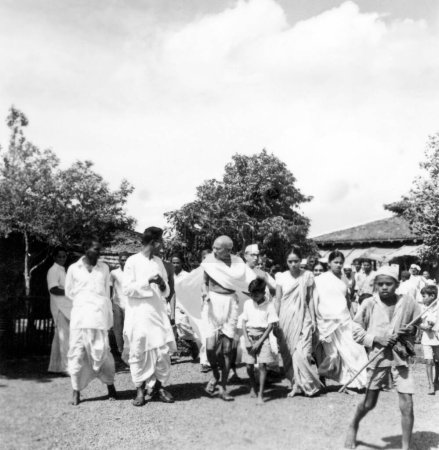 Foto de Mahatma Gandhi acompañado por el periodista Shailendra Chatterjee 4º de l, Pyarelal Nayar r detrás de Mahatma Gandhi y Abha Gandhis hermana Vinabehn Patel 3er r de Mahatma Gandhi y otros caminando en Sevagram Ashram, 1944 - Imagen libre de derechos
