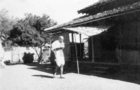 Photo for Mahatma Gandhi , walking a building Sevagram Ashram , 1940 , India - Royalty Free Image