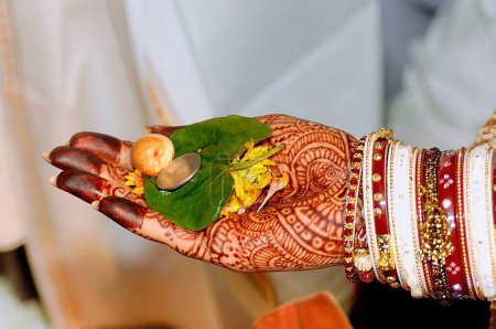 Betel leaf supari and coin in hand palm of bride performing vidhi in marriage ceremony