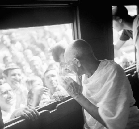 Téléchargez les photos : Mahatma Gandhi, assis dans un train et interagissant avec des personnes debout sur le quai, 1940 - en image libre de droit