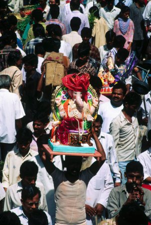 Photo for Man holding statue on his forehead for Ganesh ganpati Festival Elephant head Lord procession , bombay mumbai, maharashtra , india - Royalty Free Image