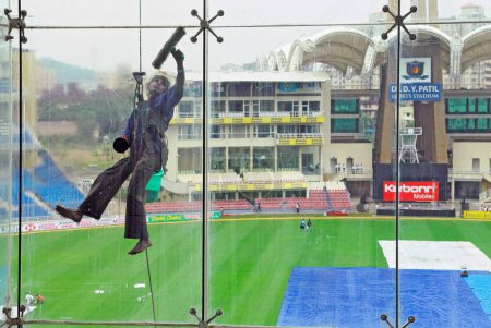 Foto de Limpiador de vidrio en el estadio de cricket D Y Patil, Nerul, Navi Bombay Mumbai, Maharashtra, India - Imagen libre de derechos