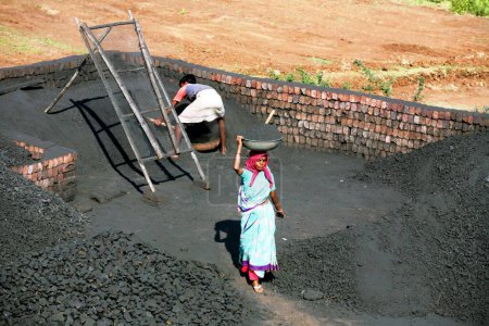Foto de Trabajadores de ladrillos tomando carbón para mezclarse con barro para hacer ladrillos en la fábrica de ladrillos en un pueblo de Sangli; Maharashtra; India - Imagen libre de derechos
