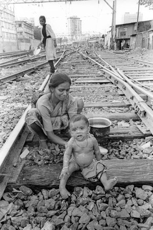 Foto de Madre bañando a su hijo en vías férreas en Wadala, Bombay Mumbai, Maharashtra, India - Imagen libre de derechos