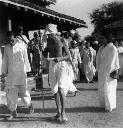 Téléchargez les photos : Mahatma Gandhi marche avec Dhamodar Mundra, collègue de Vinoba Bhave et Sushila Nayar à l'Ashram de Sevagram, 1941 - en image libre de droit