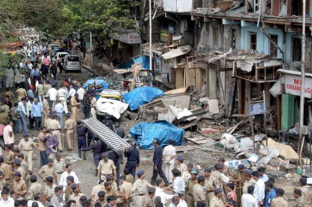 Foto de Policías inspeccionando el sitio de la explosión de bombas también bomberos que llevan escalera en el Bazar Zaveri en la ocupada zona de Kalbadevi; Bombay Mumbai, Maharashtra, India 26 de agosto de 2003 - Imagen libre de derechos