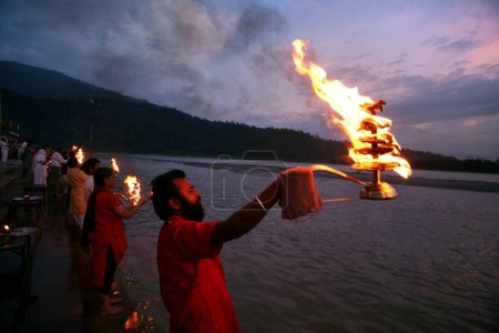 Foto de Sacerdotes haciendo las oraciones vespertinas del río Ganga en las orillas del río Rishikesh en Uttaranchal, India - Imagen libre de derechos