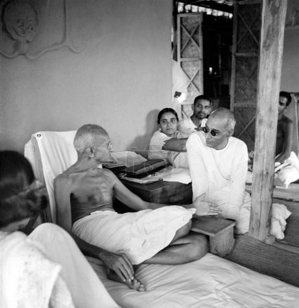 Téléchargez les photos : Mahatma Gandhi parlant avec son collègue Chakravarti Rajagopalachari dans sa cabane à l'Ashram de Sevagram, Vardha, Maharashtra, Inde, 1942 - en image libre de droit