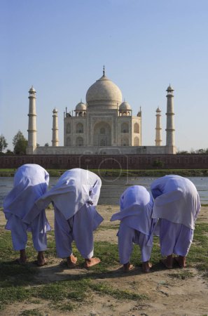 Téléchargez les photos : Jeunes garçons musulmans pratiquant la prière religieuse Namaz devant Taj Mahal Septième merveilles du monde sur la rive sud de la rivière Yamuna, Agra, Uttar Pradesh, Inde Site du patrimoine mondial de l'UNESCO - en image libre de droit