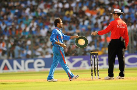 Téléchargez les photos : Le joueur indien sachin Tendulkar remet sa casquette à l'arbitre Simon Taufel avant le bowling lors de la finale de la Coupe du monde de cricket ICC contre Sri Lanka au stade Wankhede à Mumbai en Inde le 02 avril 2011 - en image libre de droit
