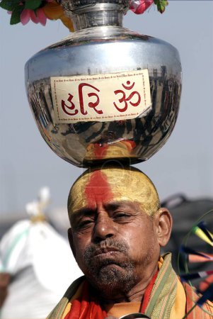 Photo for A saint, sadhu balance a stainless steel jar with flowers on his head, Ardh Kumbh Mela, one of the worlds largest religious festivals at Allahabad, Uttar Pradesh, India - Royalty Free Image