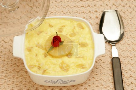 Photo for Pudding made of song cake vanilla custard and pineapple pieces with glass lid red rose in centre and serving spoon and served as dessert after lunch or dinner ; Pune ; Maharashtra ; India - Royalty Free Image