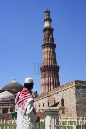 Téléchargez les photos : Garçon musulman parlant sur téléphone portable à Qutab Minar Sun Dial construit en 1311 tour de grès rouge, art indo-musulman, sultanat de Delhi, Delhi, Inde Site du patrimoine mondial de l'UNESCO - en image libre de droit