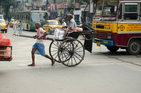 Photo for Man crossing with pulling hand rickshaw Kolkata West Bengal India Asia - Royalty Free Image