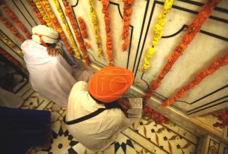 Photo for Sikh devotee reading holy scriptures, celebrations of 300th year of consecration of perpetual Guru Granth Sahib; Sachkhand Saheb Gurudwara in Nanded, Maharashtra, India - Royalty Free Image