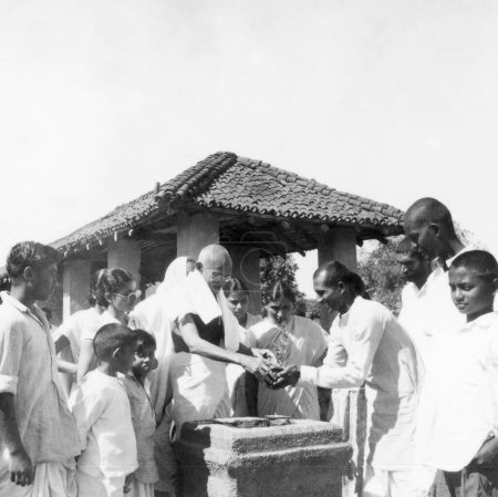 Téléchargez les photos : Mahatma Gandhi, Durga Mehta et d'autres lors d'une cérémonie de plantation d'arbres tulsi à l'Ashram de Sevagram, 1946 NO MR - en image libre de droit
