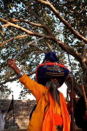 Foto de Nihang o Sikh guerrero en pagdi o tocados portando espada y palo de madera durante las celebraciones de Hola Mohalla en Anandpur sahib en el distrito de Rupnagar, Punjab, India - Imagen libre de derechos