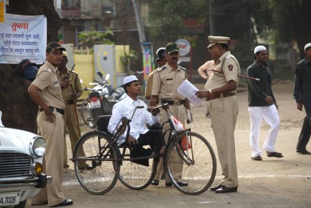 Téléchargez les photos : Un policier interrogeant un handicapé qui est arrivé pour Eid al Fitr ou Ramzan id namaaz à Lashkar, e, terrain d'Eidgaah lors d'un contrôle de sécurité, Malegaon, Maharashtra, Inde - en image libre de droit