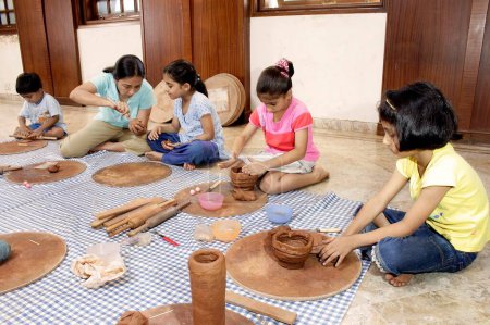 Téléchargez les photos : Cours de poterie pour enfants, potier enseignant aux enfants comment faire du pot sur roues avec d'autres techniques - en image libre de droit