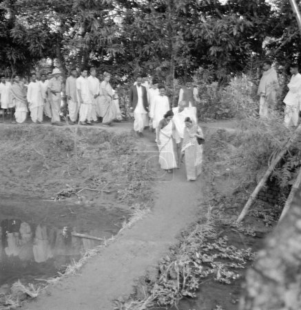 Téléchargez les photos : Mahatma Gandhi et son parti passant un barrage alors qu'ils étaient en marche à travers la zone touchée par les émeutes musulmanes hindoues au Noakhali Bengale oriental, novembre 1946, Inde - en image libre de droit