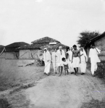 Téléchargez les photos : Mahatma Gandhi et d'autres marchant dans l'ashram de Sevagram, 1938, Rajkumari Amrit Kaur, Inde - en image libre de droit