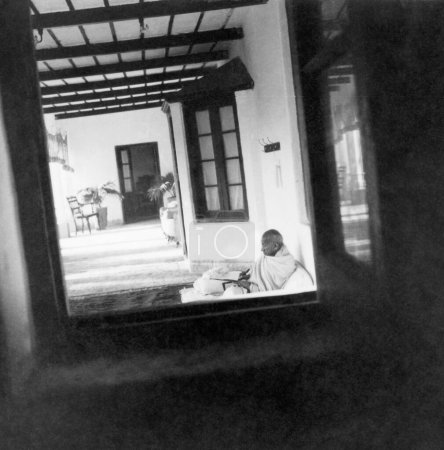 Photo for Mahatma Gandhi , seen through a window , writing during his visit to the North West Frontier Provinces to Afghanistan , October 1938 - Royalty Free Image
