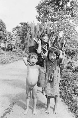 Photo for Old lady from Hill Miri tribe with grandchildren carrying wood on her back, Arunachal Pradesh, India 1982 - Royalty Free Image