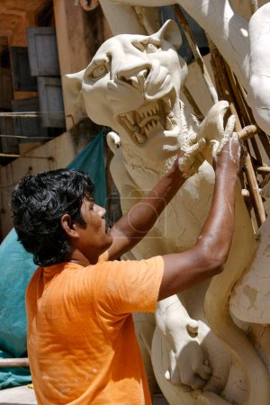 Téléchargez les photos : Sculpteur faisant Sinha Vahini Lion équitation déesse Durga Kali sculpture à l'aide d'argile pour la préparation de Durga Pooja ; Rajkot ; Gujarat ; Inde - en image libre de droit