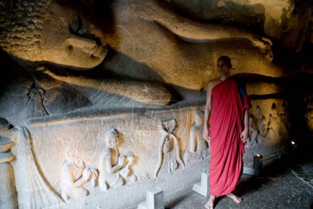 Téléchargez les photos : Moine bouddhiste debout au parinirvana la grande statue de mort de Bouddha ; Grottes Ajanta ; Aurangabad ; Maharashtra ; Inde - en image libre de droit