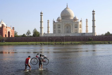 Téléchargez les photos : Homme portant un vélo dans la rivière Yamuna Taj Mahal Septième merveilles du monde, Agra, Uttar Pradesh, Inde Site du patrimoine mondial de l'UNESCO - en image libre de droit