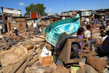 Téléchargez les photos : Les habitants des bidonvilles s'assoient avec leurs biens après la démolition des bidonvilles à l'aéroport du Sahar Aéroport international Chatrapati Shivaji à Bombay Mumbai, Maharashtra, Inde - en image libre de droit