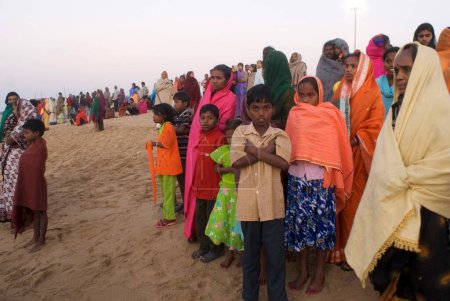 Foto de La gente se reúne temprano en la mañana para vislumbrar el primer rayo de sol que golpeará la tierra en la India en Chandrabhaga cerca del templo de Konarak, Konarak, Orissa, India - Imagen libre de derechos