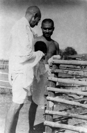 Téléchargez les photos : Mahatma Gandhi donne l'argent qui a été recueilli lors de son dernier anniversaire à Kanu Gandhi, 1939 - en image libre de droit