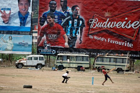 Foto de Niños jugando al cricket frente al acaparamiento mostrando al futbolista internacional 4, May, 2008 - Imagen libre de derechos