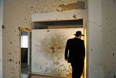 Téléchargez les photos : Juif orthodoxe inspecte les murs endommagés dans l'explosion de grenade et des marques de balle à la maison nariman, Bombay Mumbai, Maharashtra, Inde - en image libre de droit