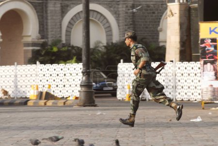 Téléchargez les photos : Commando en fuite devant l'hôtel Taj Mahal lors d'une attaque terroriste perpétrée par des moudjahidines décanes à Mumbai, Maharashtra, Inde 26-novembre-2008 - en image libre de droit
