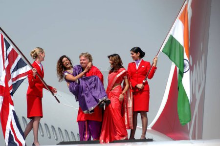 Téléchargez les photos : Propriétaire de Virgin Atlantic Airways Richard Branson ainsi que des modèles indiens et hôtesse de l'air tenant le drapeau de l'Inde et de la Grande-Bretagne sur les ailes d'Airbus A340, 600 - en image libre de droit