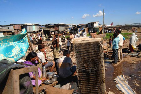 Téléchargez les photos : Les habitants des bidonvilles s'assoient avec leurs biens après la démolition des bidonvilles à l'aéroport du Sahar Aéroport international Chatrapati Shivaji à Bombay Mumbai, Maharashtra, Inde - en image libre de droit
