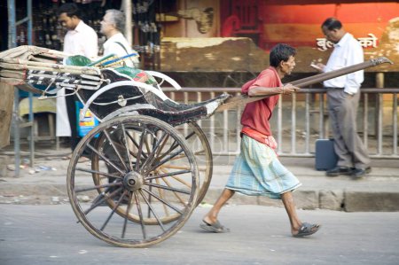 Téléchargez les photos : Scène de rue, tireur de pousse-pousse tirant un véhicule vide, Calcutta maintenant Kolkata, Bengale occidental, Inde - en image libre de droit