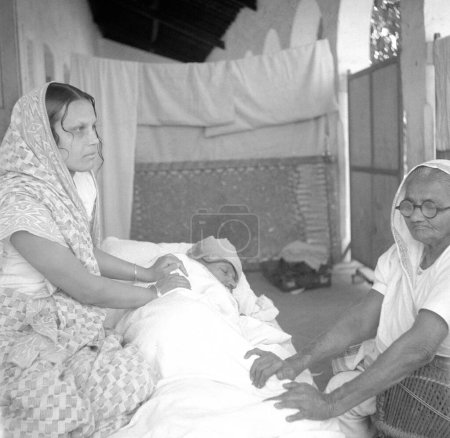 Photo for Mahatma Gandhi receiving massage from Vijayalaxmi Gandhi and his sister Raliatbehn during his fast at Rashtriyashala Ashram, Rajkot, Gujarat, India, March 1939 - Royalty Free Image
