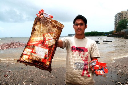 Téléchargez les photos : Homme montrant des paquets de biscuits imbibés d'huile en raison de l'abordage du navire porte-conteneurs Chitra en mer Bombay Mumbai, Maharashtra, Inde 9, Août, 2010 - en image libre de droit