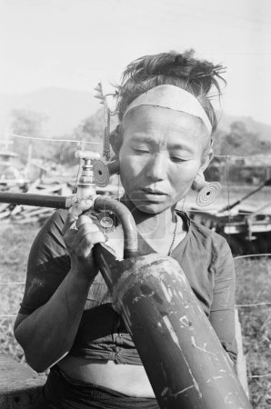 Téléchargez les photos : Dame Idu Pishmi remplissant une pipe en bambou avec mangeur, tribu Hill Miri, Arunachal Pradesh, Inde 1982 - en image libre de droit