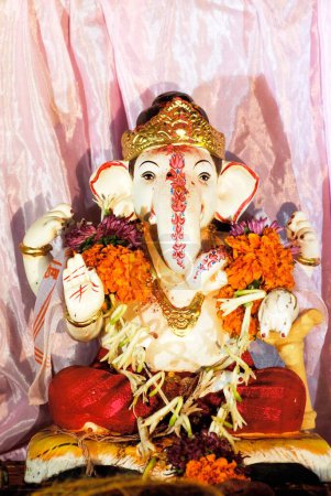 Small idol of Lord Ganesh wearing garland of flowers elephant headed god ; Ganapati festival at Pune ; Maharashtra ; India