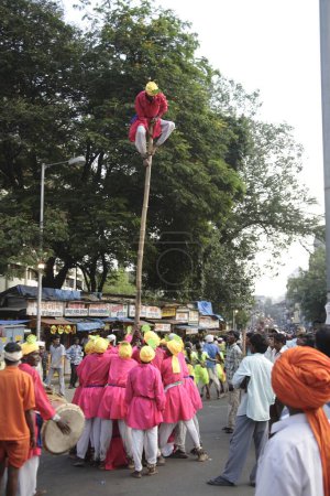 Téléchargez les photos : Adivasi de Mokhada exécutant des acrobaties sur les rythmes du tambour lors de la procession religieuse à Court Naka, Thane, Maharashtra, Inde, - en image libre de droit