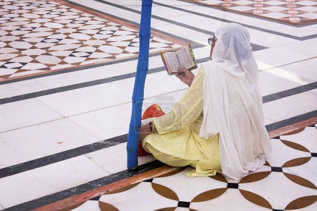 Photo for Sikh woman praying sitting on the floral structure pattern of the white marble inside Swarn Mandir Golden temple, Amritsar, Punjab, India - Royalty Free Image