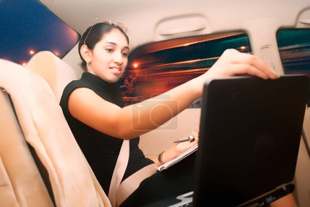 South Asian Indian young executive lady in a Honda car looking to the mobile with smile