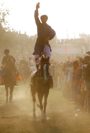 Téléchargez les photos : Guerrier sikh équilibrage à cheval dans hola mohalla festival, Anandpur Sahib, Punjab, Inde - en image libre de droit
