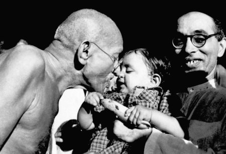 Foto de Mahatma Gandhi presenta un regalo de cumpleaños a Nandini, sobrina de Pyarelal Nayar en el Ashram Sevagram, agosto de 1944, ashramita Anand Hingorani - Imagen libre de derechos