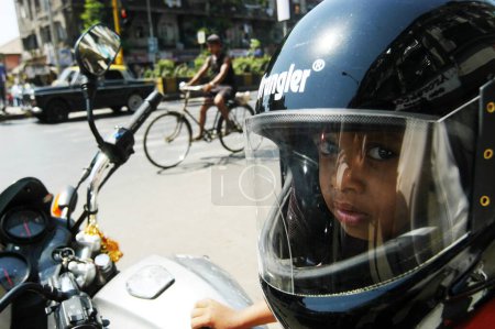 Photo for Boy wears helmet sits on two wheeler or motor bike in Bombay Mumbai, Maharashtra, India - Royalty Free Image