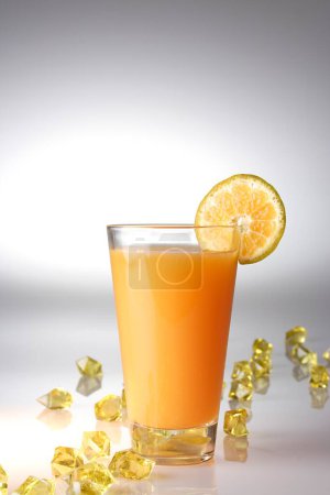 Foto de Bebidas, Zumo de naranja con una rebanada de naranja sobre fondo blanco con piezas acrílicas amarillas - Imagen libre de derechos